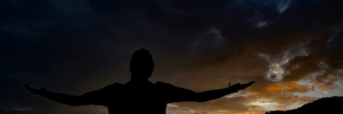 silhouette of man standing on hill during night time